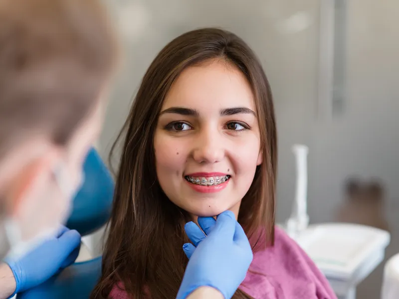 Smiling teen with metal braces during an orthodontic visit
